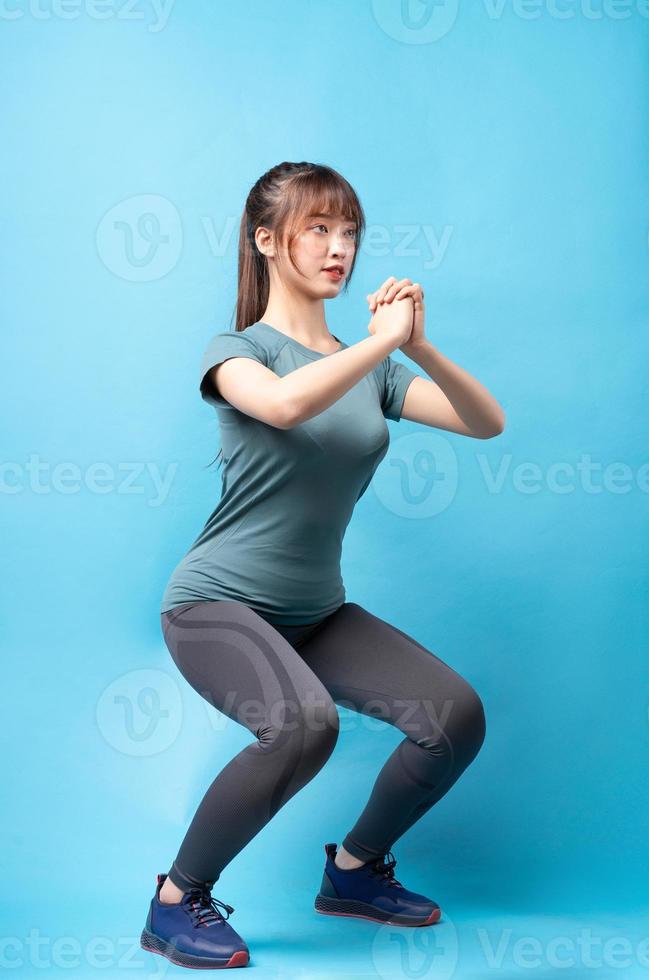 Jeune femme asiatique portant un costume de sport sur fond bleu photo