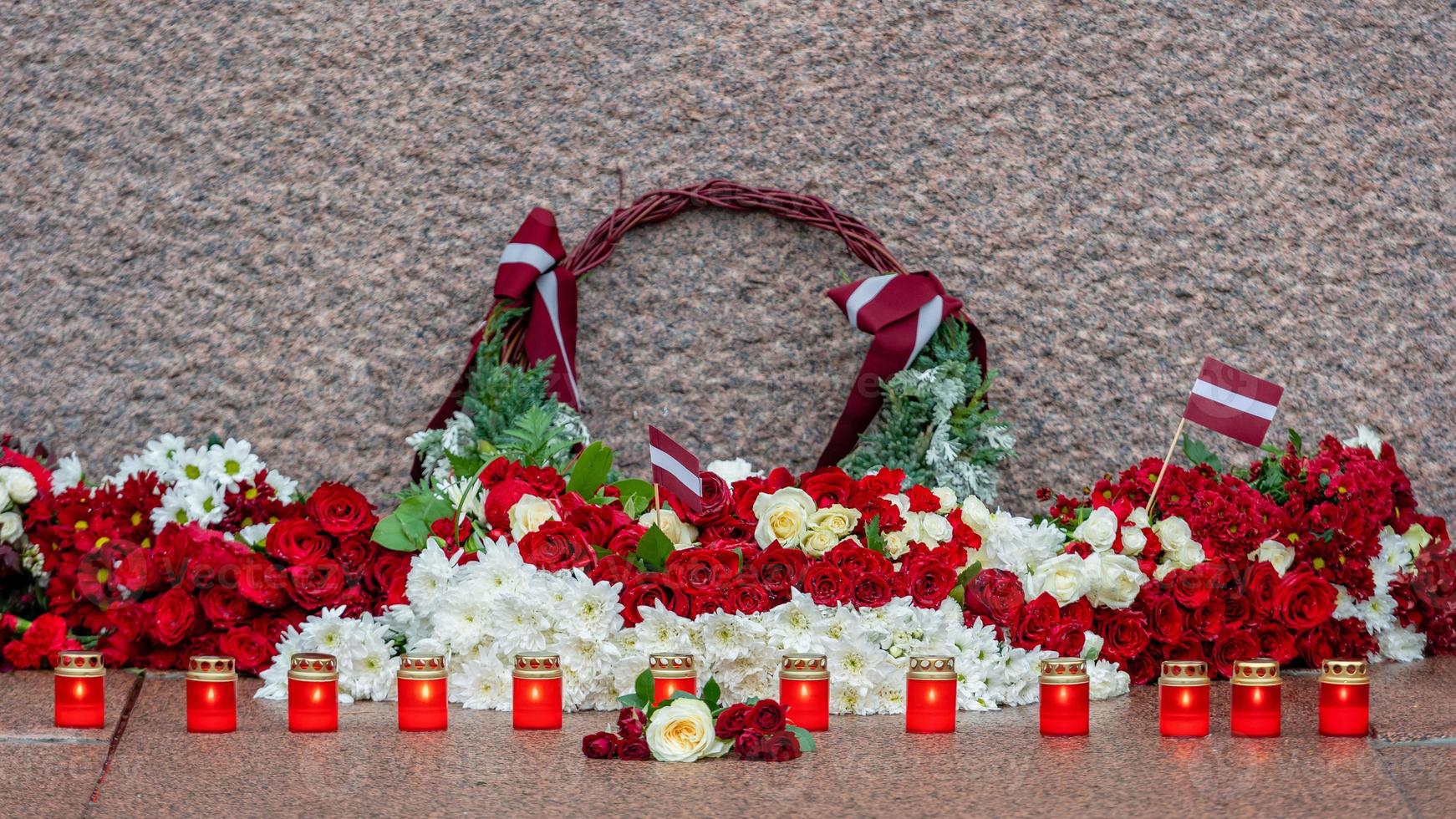 lettonie 100 ans. compositions de fleurs rouges et blanches au monument de la liberté dans la ville de riga, en lettonie photo