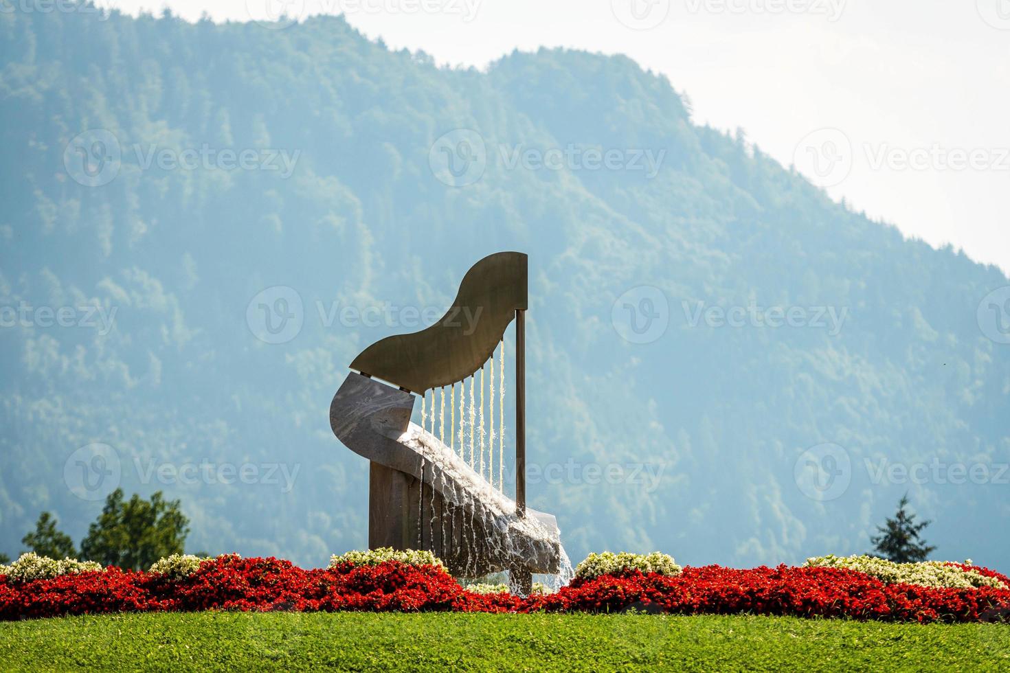la fontaine de harpe à ossiach, en autriche. forêt et montagnes en arrière-plan. photo