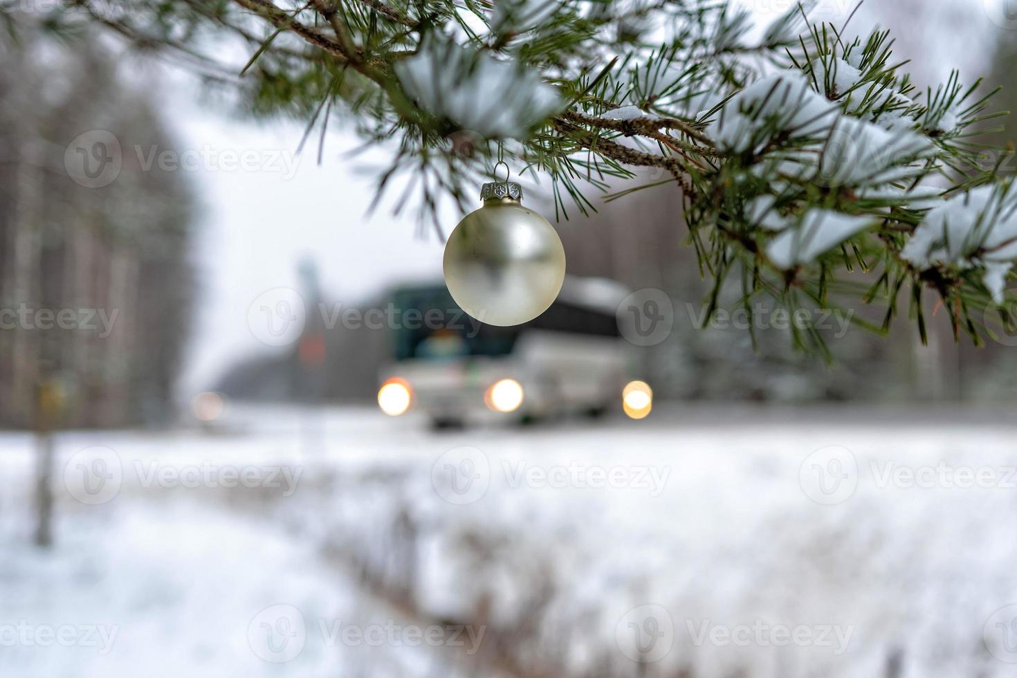 boule de noël dorée sur la branche de sapin couverte de neige à côté de l'autoroute. photo