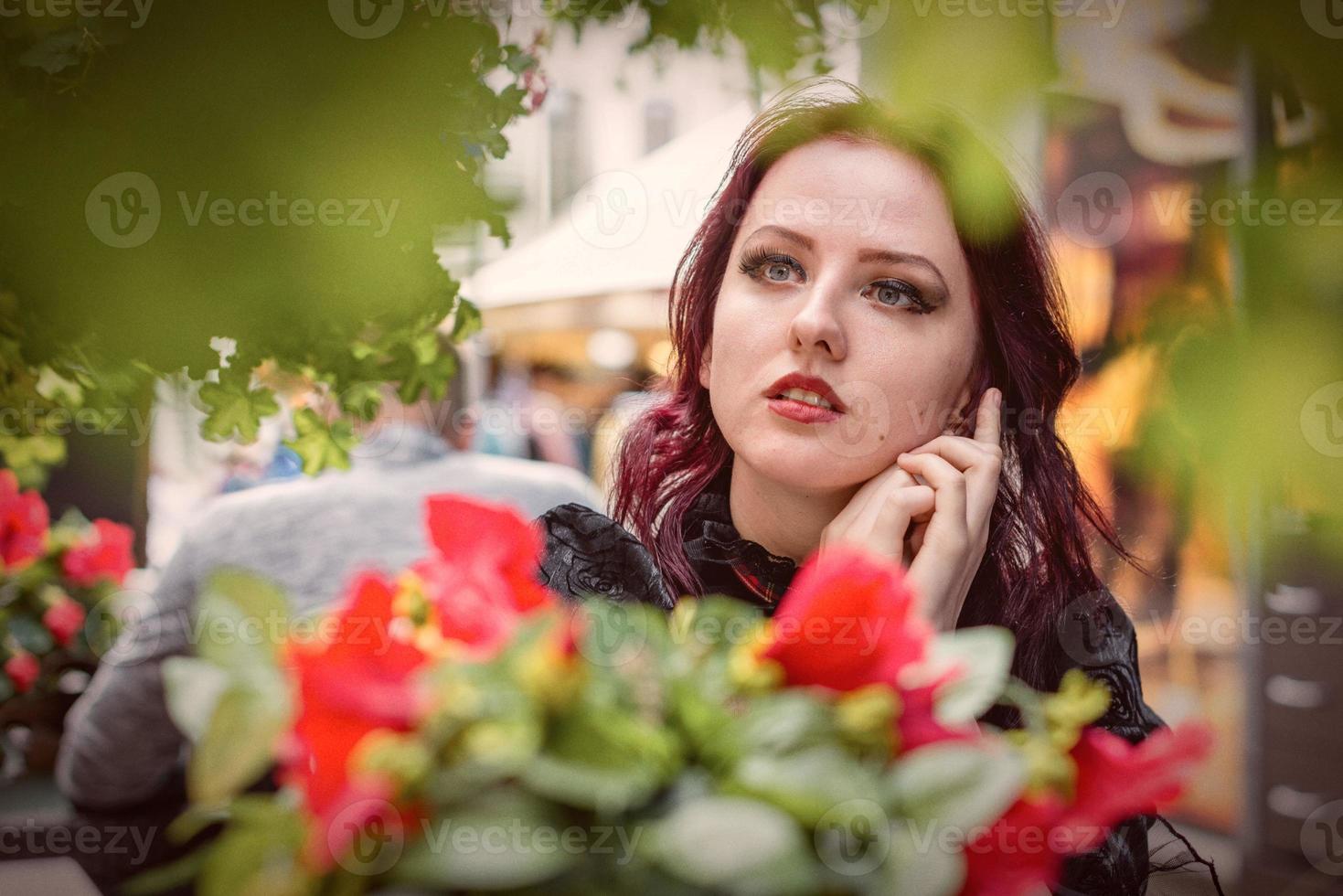 jeune femme rousse magnifique assise dans un café en plein air vêtue de vêtements de mode rétro. photo