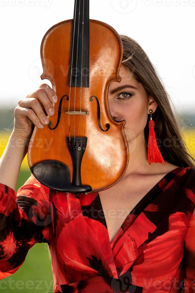 portrait d'une jeune femme positive. une partie du visage est recouverte par le manche du violon - image photo