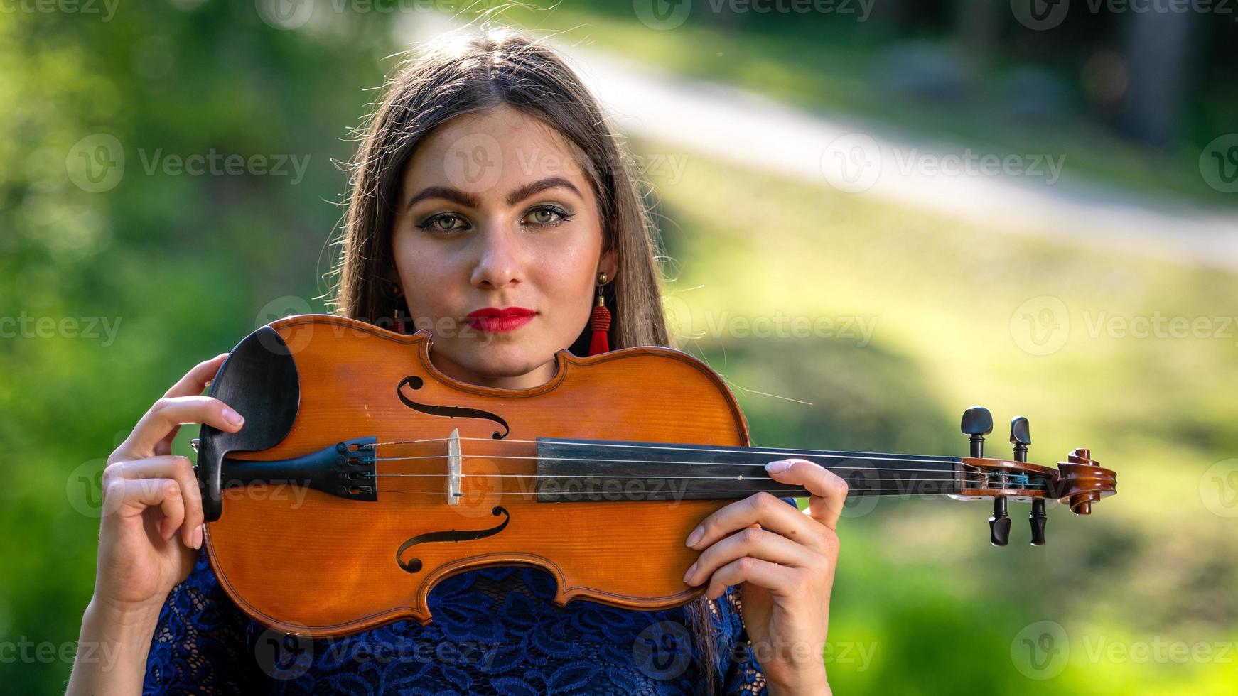 portrait d'une jeune femme positive. une partie du visage est recouverte par le manche du violon - image photo