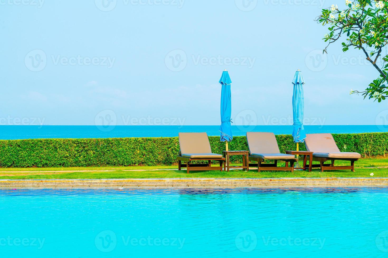 chaise piscines ou lits et parasols autour de la piscine avec fond de mer - concept de vacances et de vacances photo