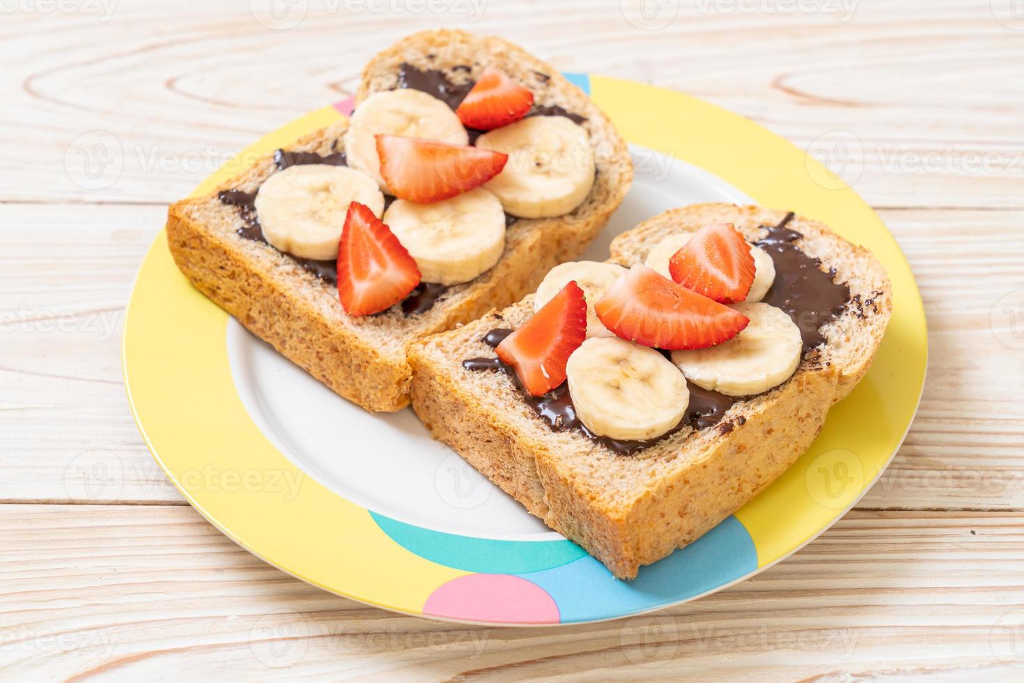 pain de blé entier grillé avec banane fraîche, fraise et chocolat pour le petit-déjeuner photo