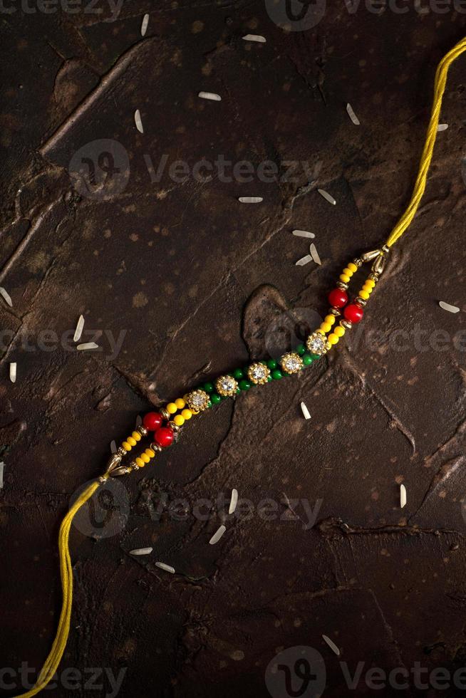 fond raksha bandhan avec un élégant rakhi et du riz dispersé. un bracelet indien traditionnel qui est un symbole d'amour entre frères et sœurs. photo