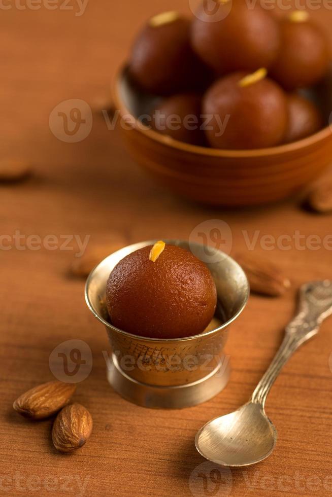 gulab jamun dans bol et bol antique en cuivre avec cuillère. dessert indien ou plat sucré. photo