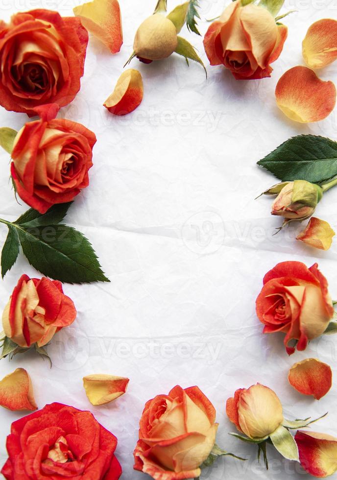 composition de fleurs. cadre fait de roses rouges et de feuilles sur fond de papier blanc photo