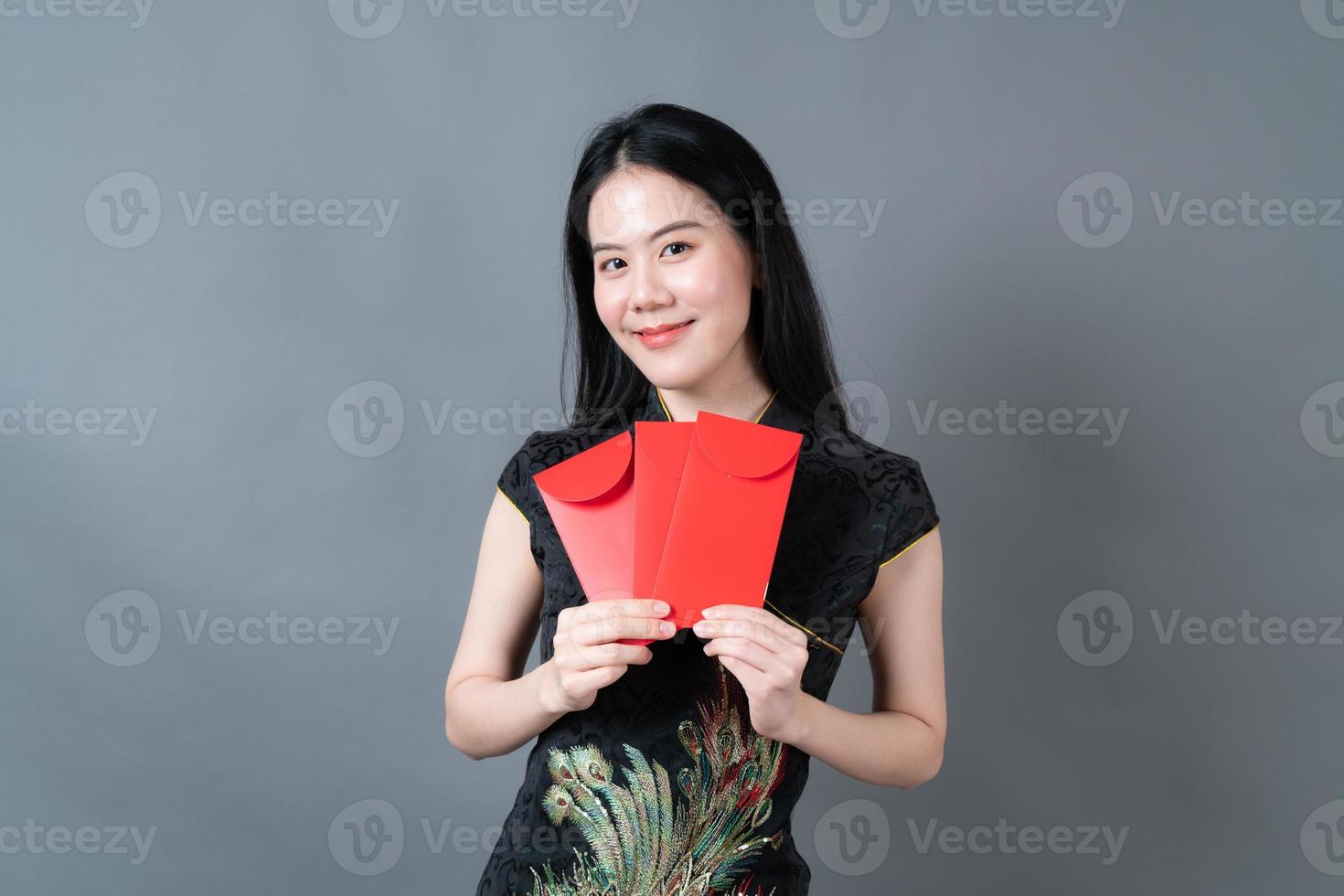 une femme asiatique porte une robe traditionnelle chinoise avec une enveloppe rouge ou un paquet rouge photo