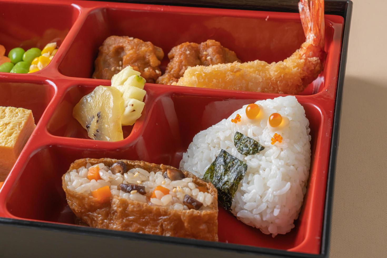 riz à sushi inari enveloppé dans du tofu séché avec crevettes frites et poulet frit dans un ensemble de bento - style de cuisine japonaise photo