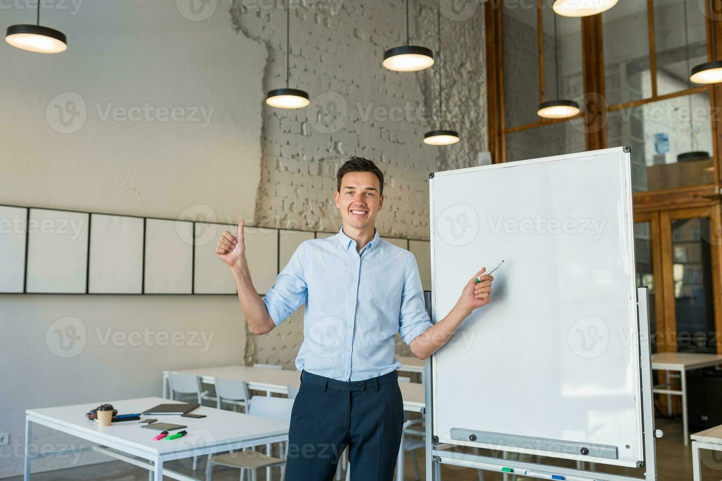 sur de soi Jeune Beau souriant homme permanent à vide blanc planche avec marqueur photo