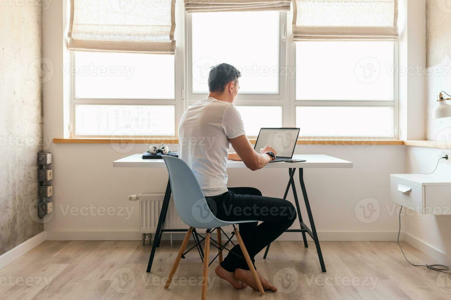 Jeune Beau homme dans décontractée tenue séance à table travail sur ordinateur portable, dactylographie, pigiste à Accueil photo