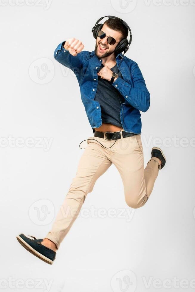 Jeune Beau content souriant homme dansant et écoute à la musique dans écouteurs photo