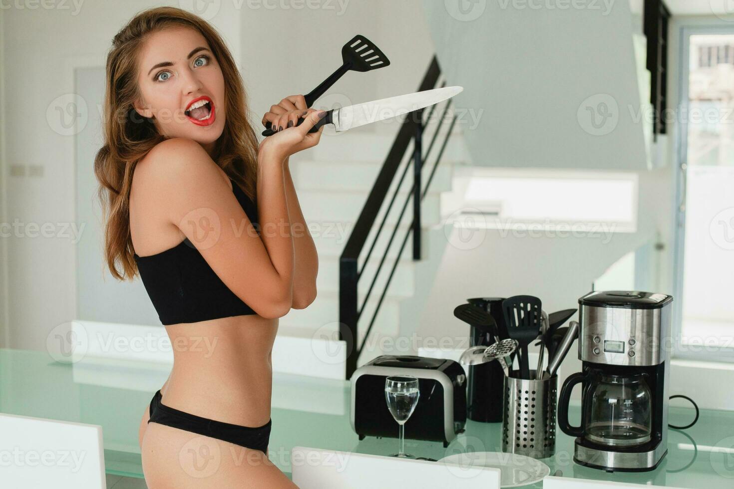 Jeune svelte magnifique femme séance sur cuisine table en portant couteau, sexy, noir sous-vêtement, femme au foyer, sensuel, manger chambre, Ménage appareils électroménagers, maigre corps, bronzé peau photo