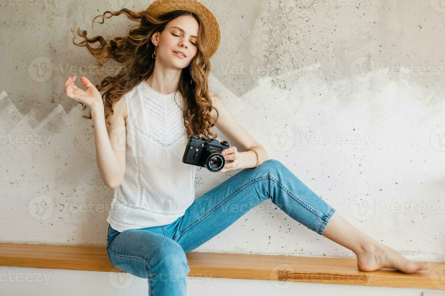 Jeune jolie souriant content femme dans paille chapeau en portant ancien photo caméra, longue frisé cheveux