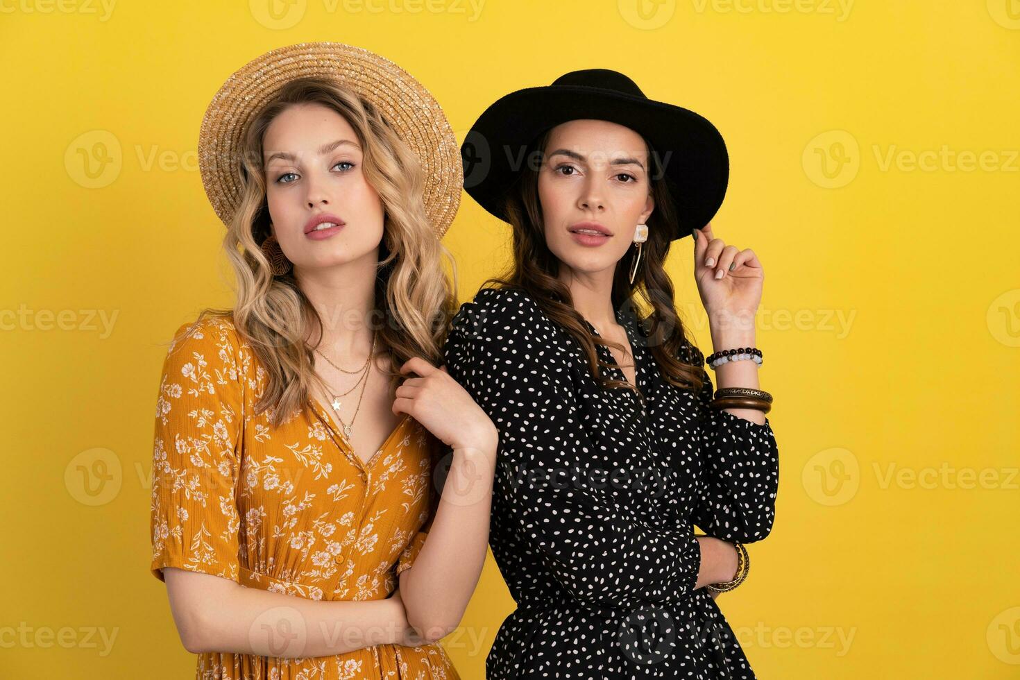 magnifique femmes copains ensemble isolé sur Jaune Contexte dans noir et Jaune robe et chapeau photo