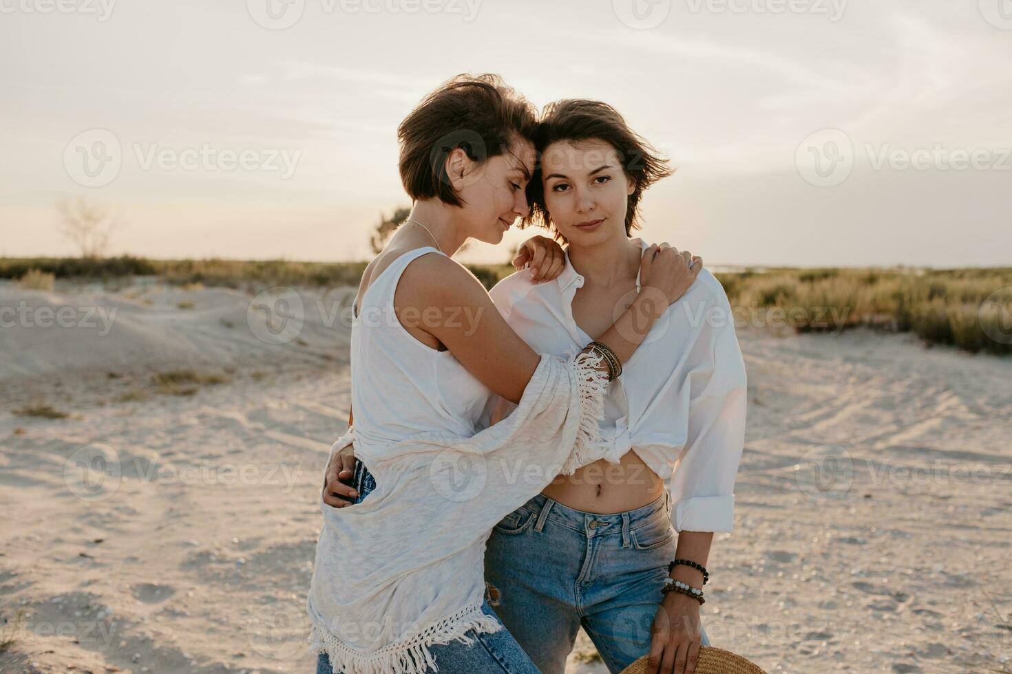 deux Jeune femmes ayant amusement sur le le coucher du soleil plage photo