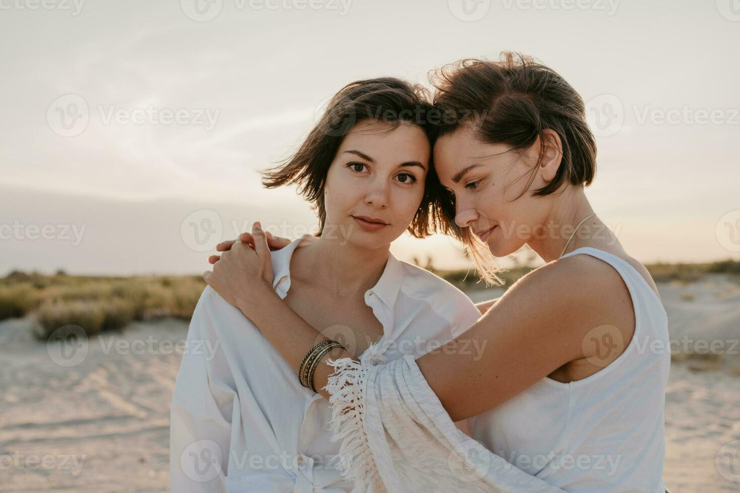 deux Jeune femmes ayant amusement sur le le coucher du soleil plage photo