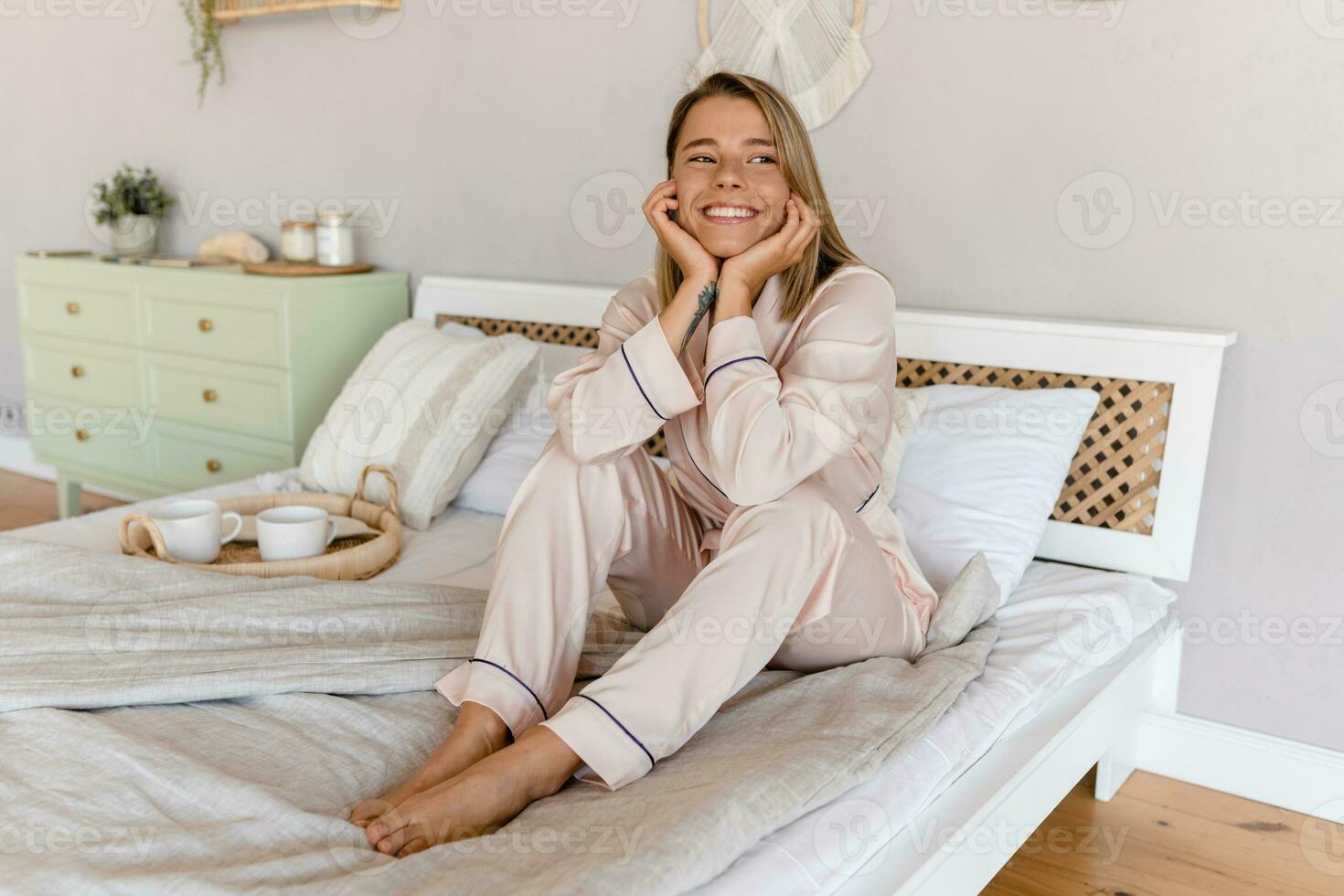 jolie souriant femme relaxant à Accueil sur lit dans Matin dans pyjamas photo