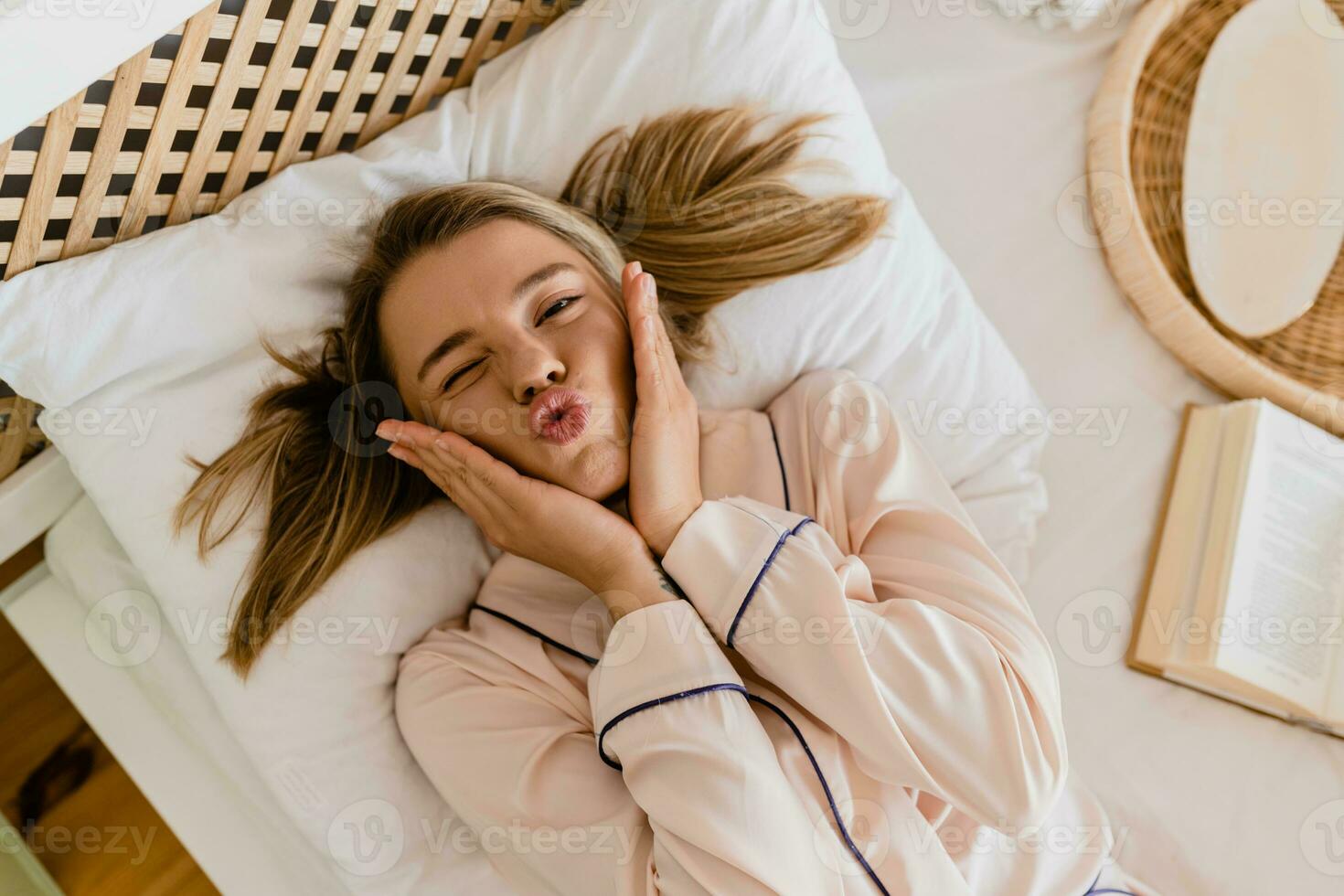 jolie souriant femme relaxant à Accueil sur lit dans Matin dans pyjamas photo