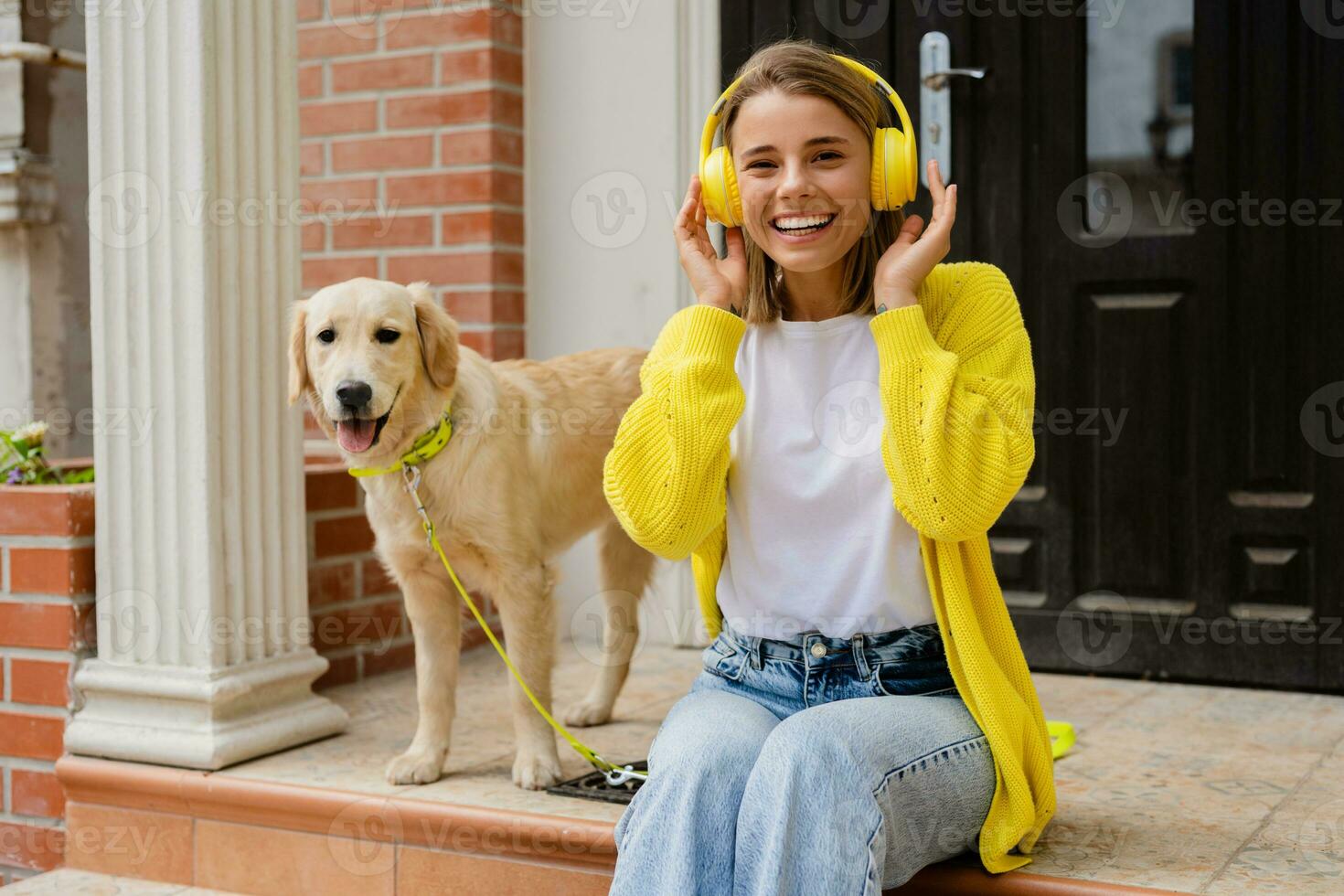 femme dans Jaune chandail en marchant à sa maison avec une chien écoute à la musique dans écouteurs photo