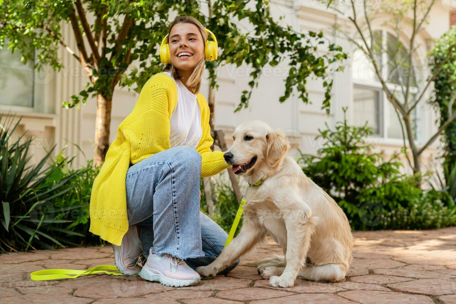 content souriant femme dans Jaune chandail en marchant à sa maison avec une chien d'or retriever photo