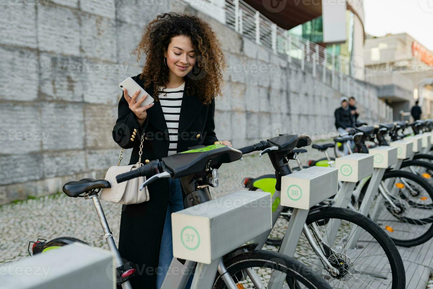 jolie frisé femme location une vélo dans rue avec un app photo