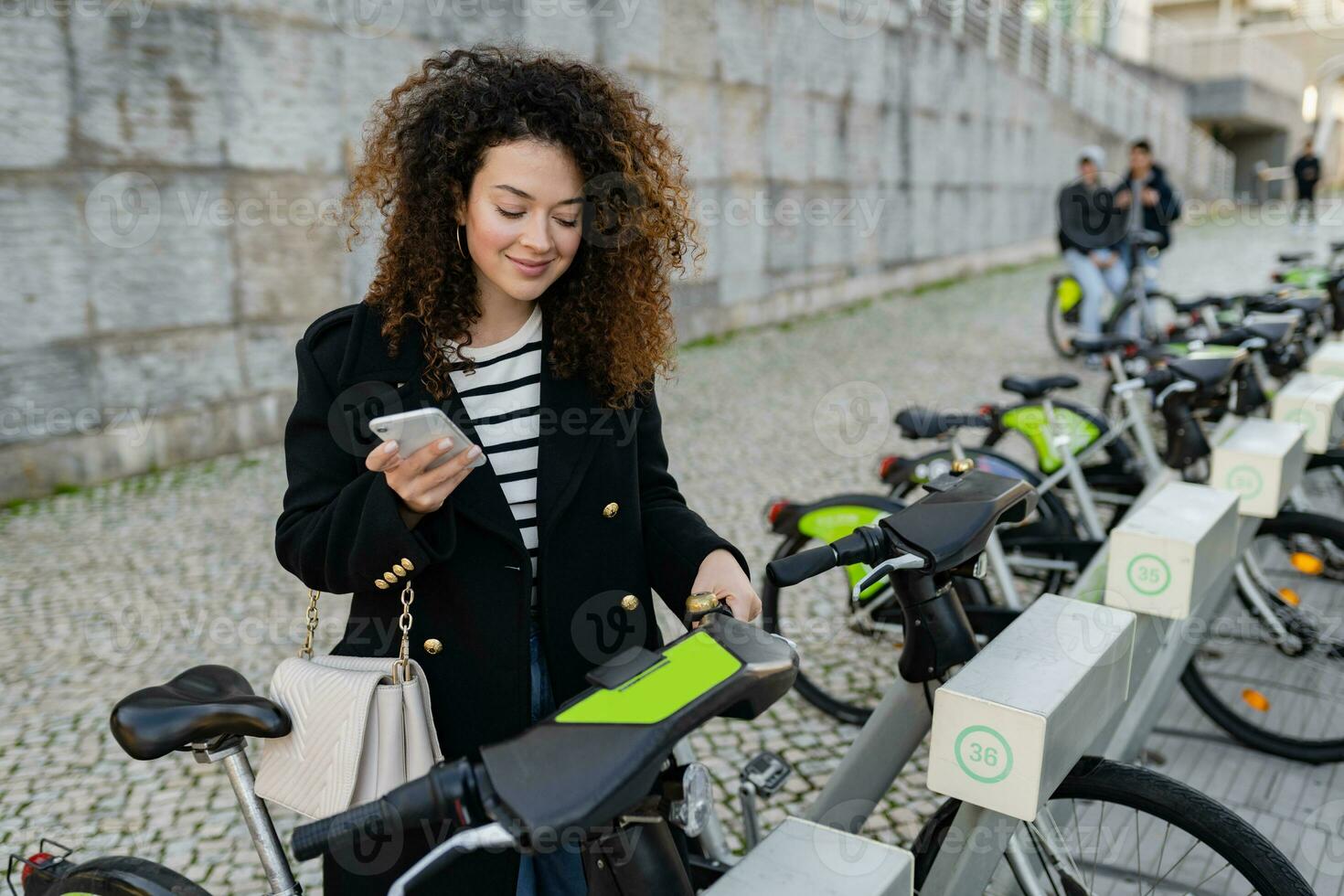 jolie frisé femme location une vélo dans rue avec un app photo