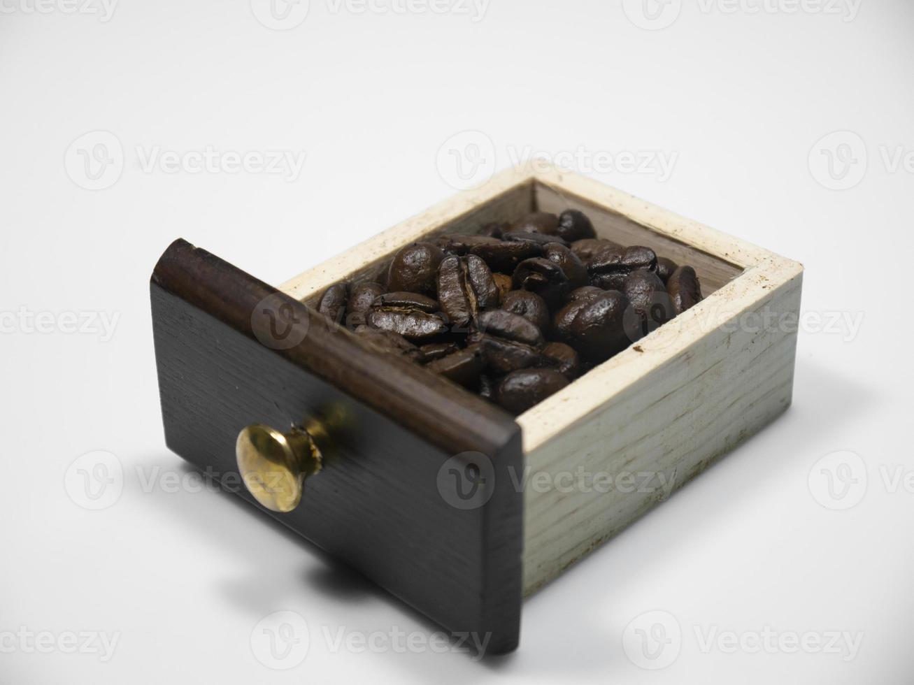 grains de café dans la petite boîte en bois du moulin à café sur fond blanc. fermer photo