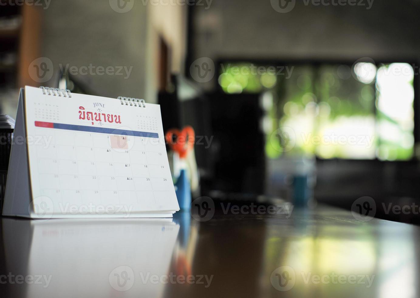 calendrier agrandi sur la table avec lumière bokeh floue en arrière-plan. concept de travail à domicile. mot thaï sur le calendrier signifie juin en anglais photo