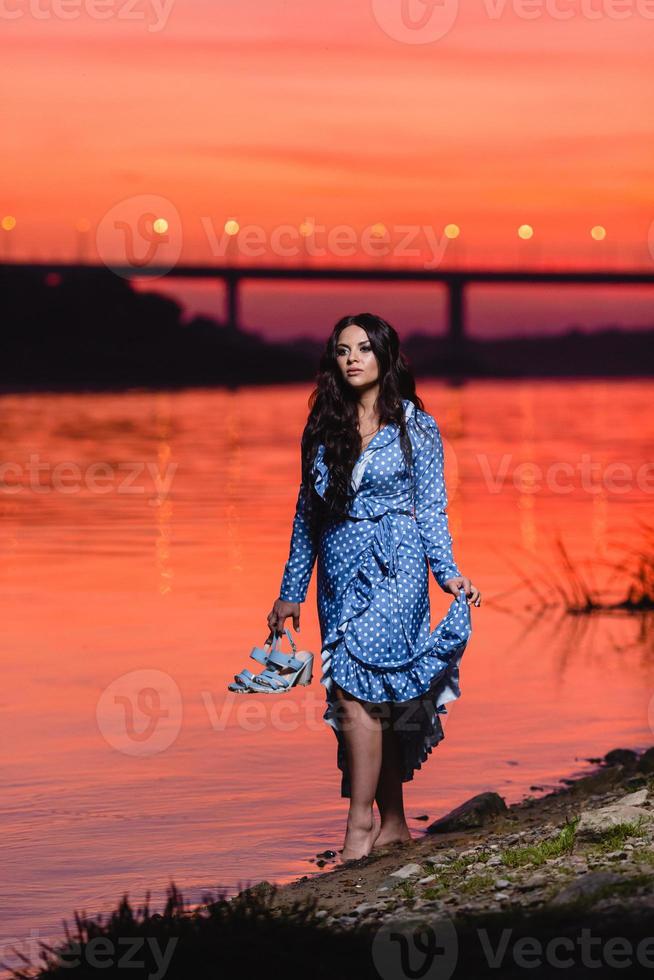 belle jeune fille aux longs cheveux ondulés noirs debout au bord de la rivière photo