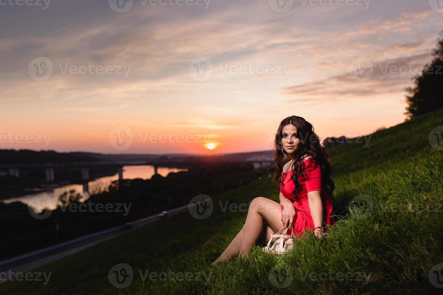 belle jeune fille assise sur une pente couverte d'herbe verte photo