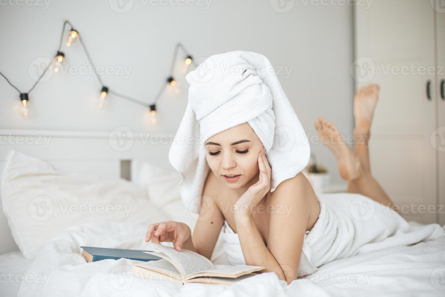 jeune femme heureuse lisant un livre papier au lit. photo