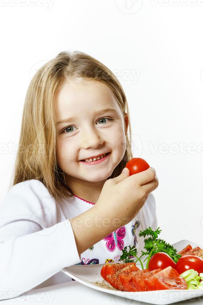 jolie petite fille avec une assiette de légumes frais photo