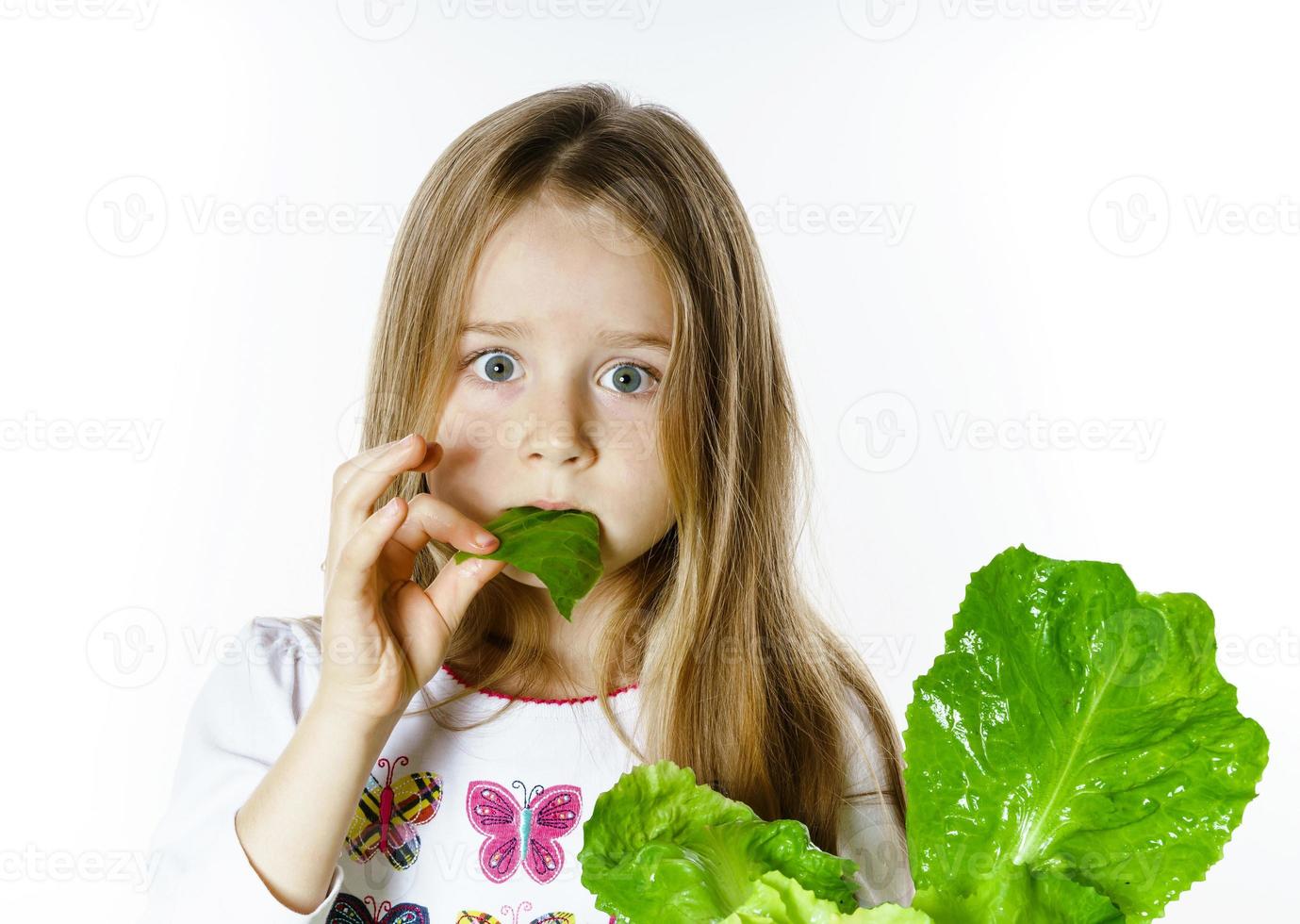 jolie petite fille posant avec des feuilles de salade fraîches photo