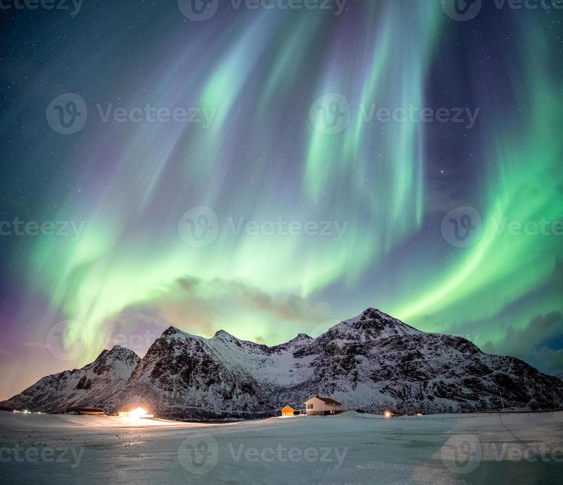 fantastique aurore boréale avec danse étoilée sur la montagne enneigée photo