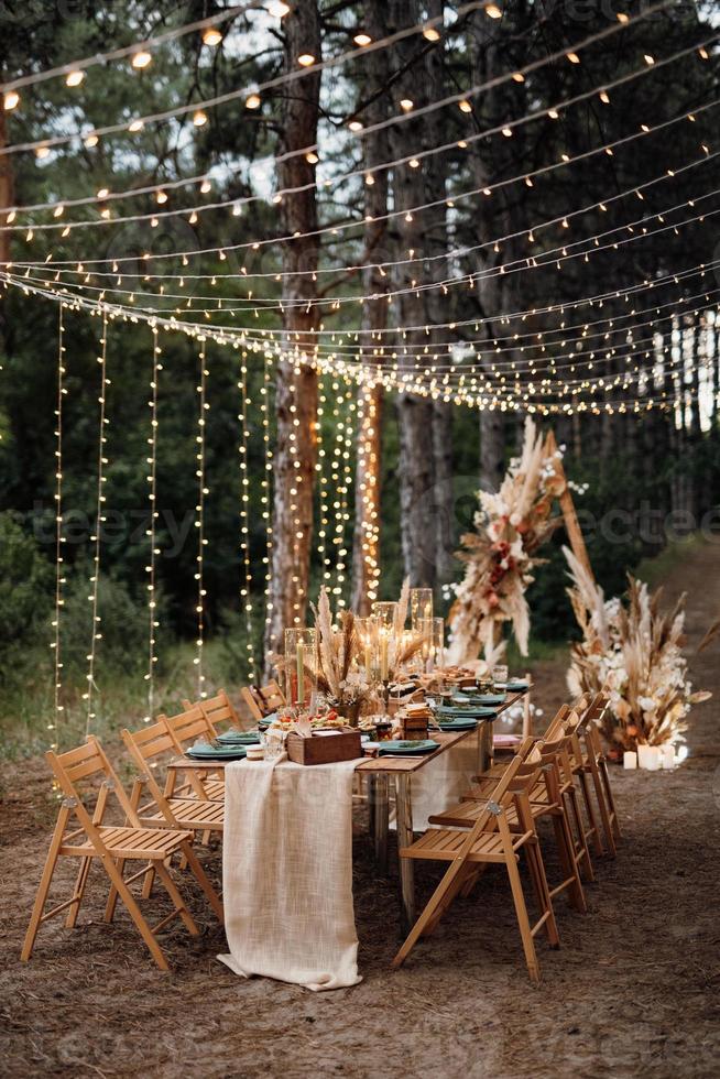 zone de banquet de mariage dans une forêt de pins avec une arche en arrière-plan photo