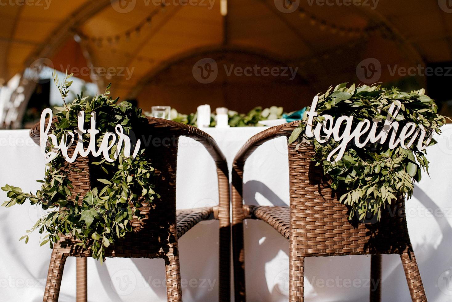 le présidium des jeunes mariés dans la salle de banquet du restaurant est décoré de bougies et de plantes vertes, le ton général de la salle est beige photo