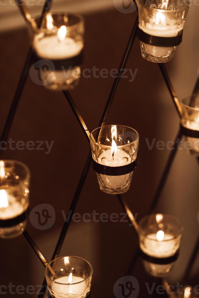 des bougies brûlent dans des verres sur l'arche de mariage photo