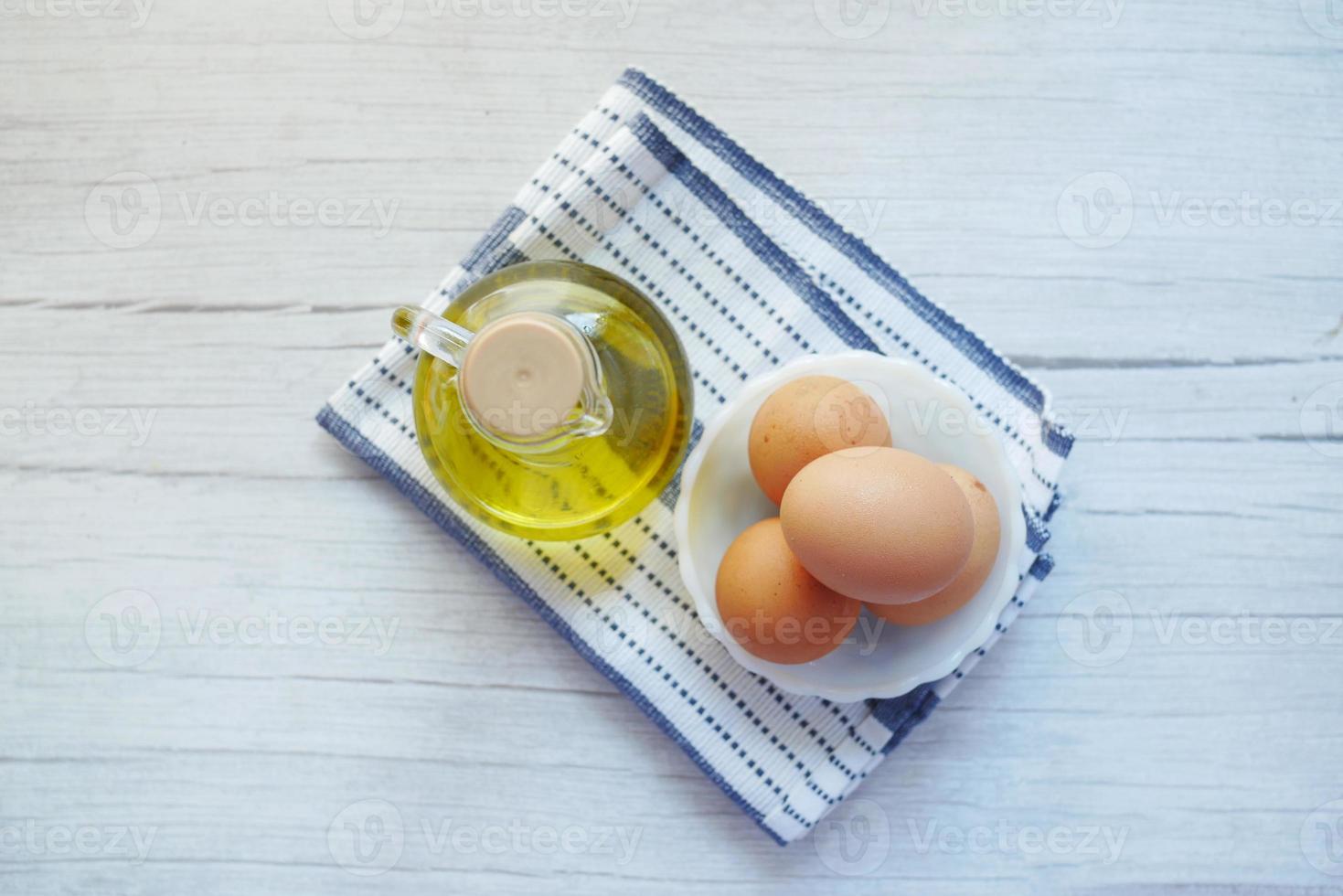 vue de dessus des œufs dans un bol et de l'huile de cuisson sur la table photo