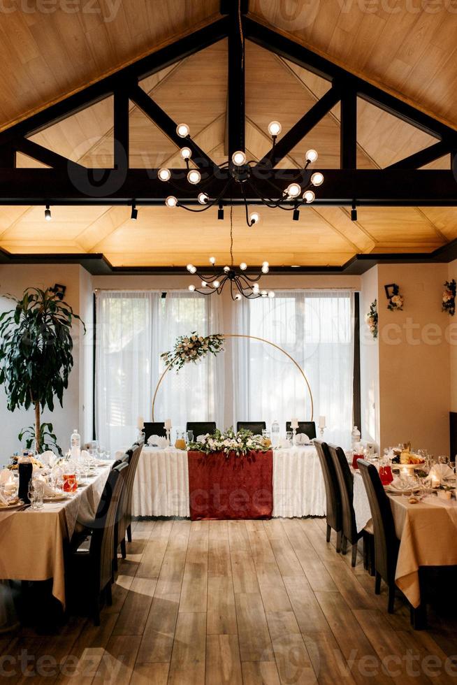 le présidium des jeunes mariés dans la salle de banquet du restaurant est décoré de bougies et de plantes vertes photo