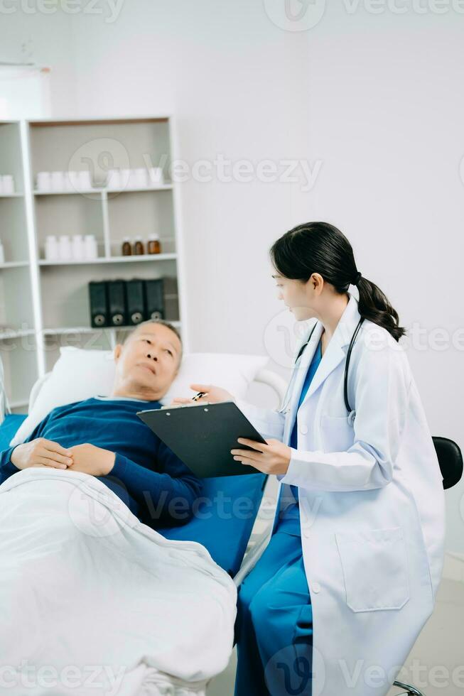 asiatique médecin dans blanc costume prendre Remarques tandis que discuter et asiatique âgé, homme patient qui mensonge sur lit avec recevoir saline Solution dans hôpital photo