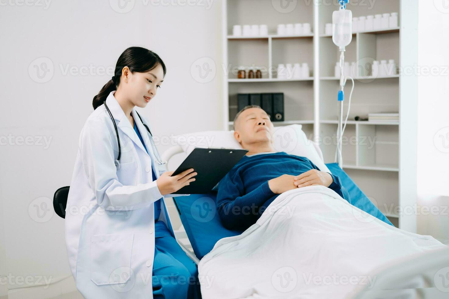 asiatique médecin dans blanc costume prendre Remarques tandis que discuter et asiatique âgé, homme patient qui mensonge sur lit avec recevoir saline Solution dans hôpital photo