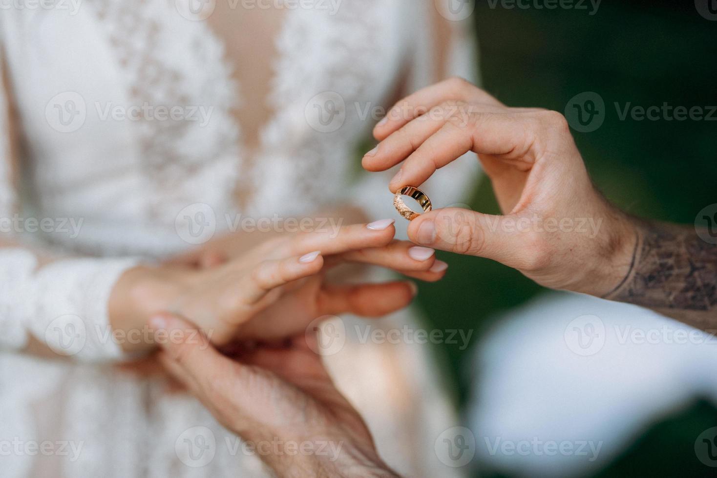 le marié met la mariée sur l'anneau de mariage photo