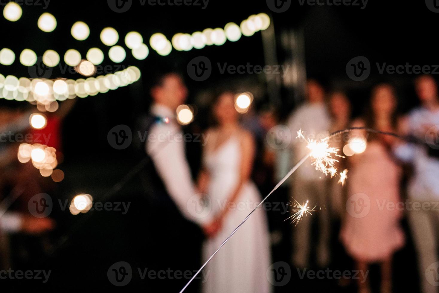 cierges magiques au mariage, un couple de jeunes mariés en arrière-plan photo