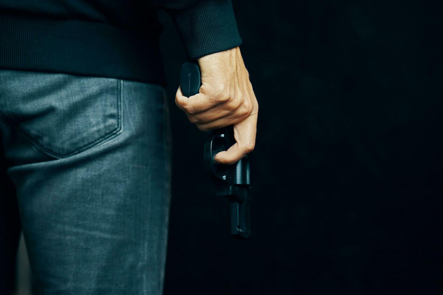 un homme vêtu de vêtements sombres tient un pistolet. photo