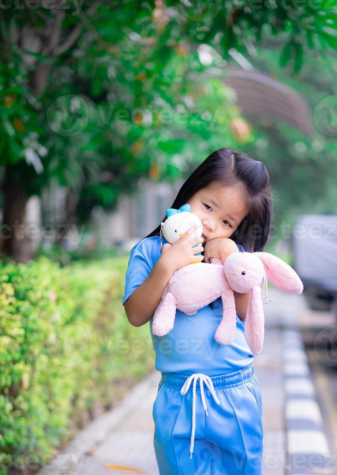 jolie petite fille asiatique avec une poupée dans le parc photo