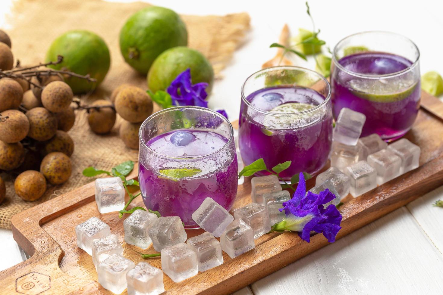 verre de jus de citron, fleurs de pois et longane sur table en bois blanc photo