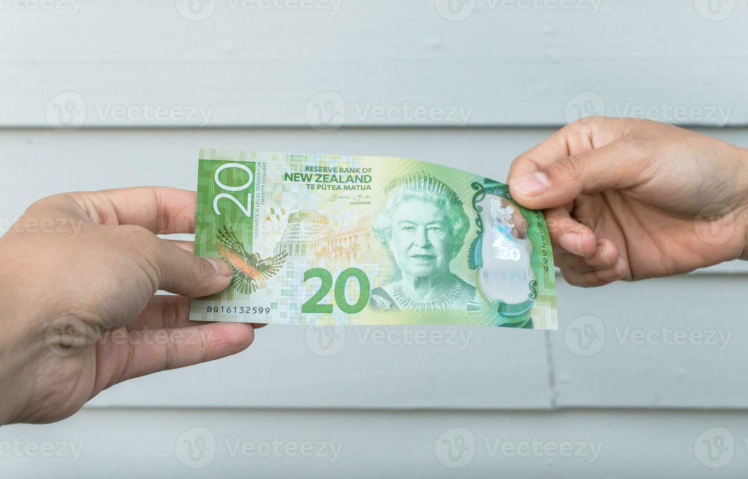 tondu coup vue de Quelqu'un donner le argent Nouveau zélande 20 dollars à chaque autre. photo