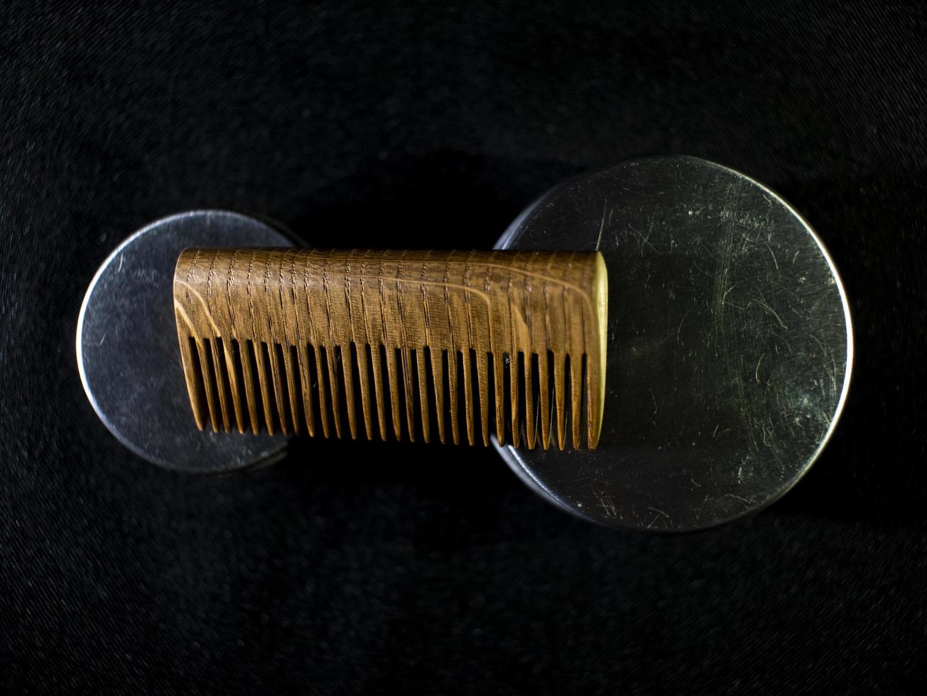 peigne en bois et pots de cire à barbe et moustache sur fond noir photo